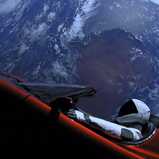 Veículo Tesla Roadster tripulado pelo boneco Starman no espaço, com o planeta Terra no fundo. O carro iniciou sua viagem pelas estrelas em fevereiro de 2018 no primeiro voo do foguete Falcon Heavy.
